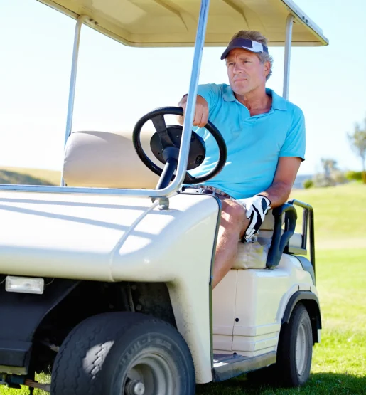 A man driving a golf cart across the field A man driving a golf cart across the field